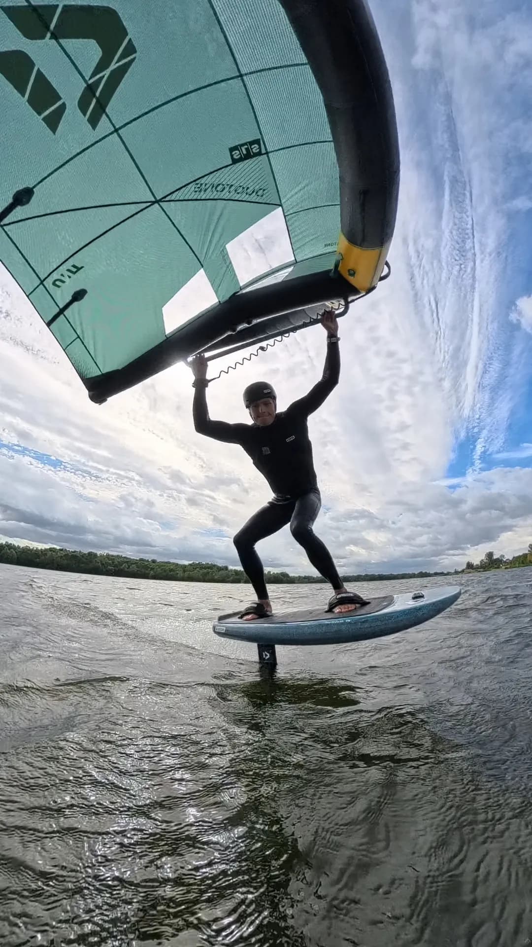Wingfoiler mit türkisfarbenem Wing auf dem Wasser